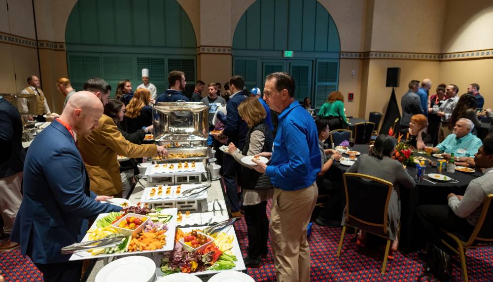 Alumni getting food from the buffet at the reception.